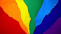 Das Bild zeigt aufeinanderliegende Papiere in Regenbogenfarben.