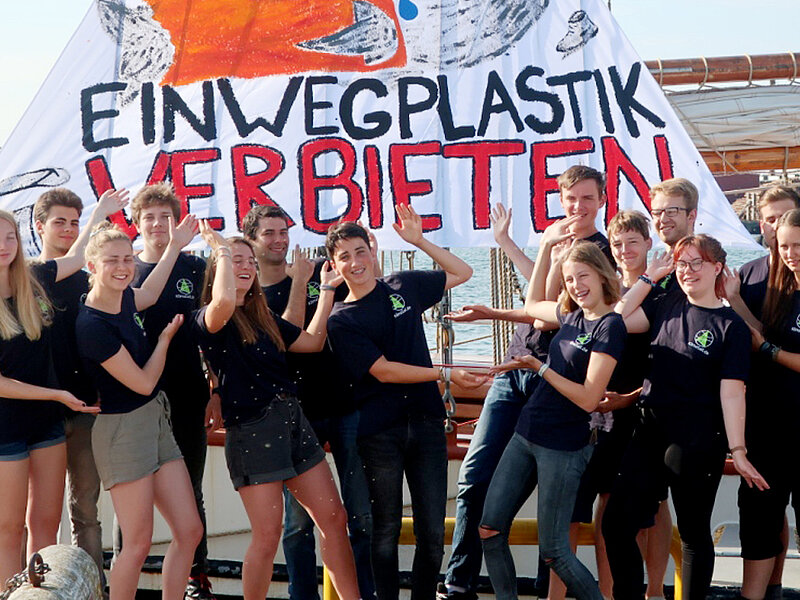 14 junge Menschen vor einem Banner mit der Aufschrift: Einwegplastik verbieten.